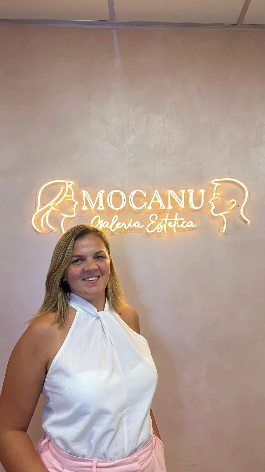 La propietaria de Mocanu Galería Estética en Murcia junto al neón del centro